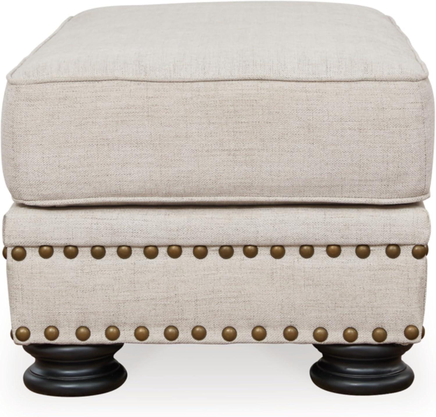 Beige Upholstered Ottoman with Nailhead Trim and Turned Legs