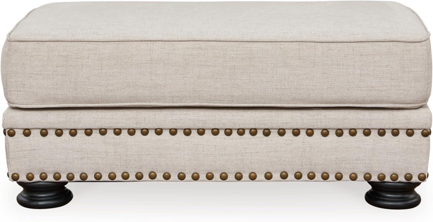 Beige Upholstered Ottoman with Nailhead Trim and Turned Legs