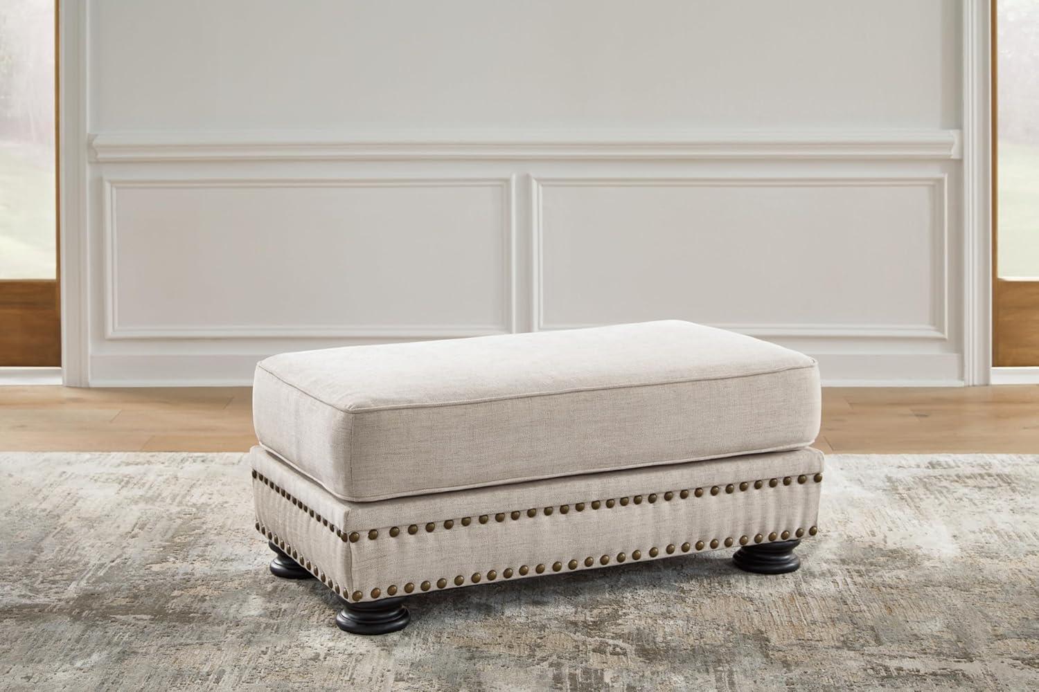 Beige Upholstered Ottoman with Nailhead Trim and Turned Legs