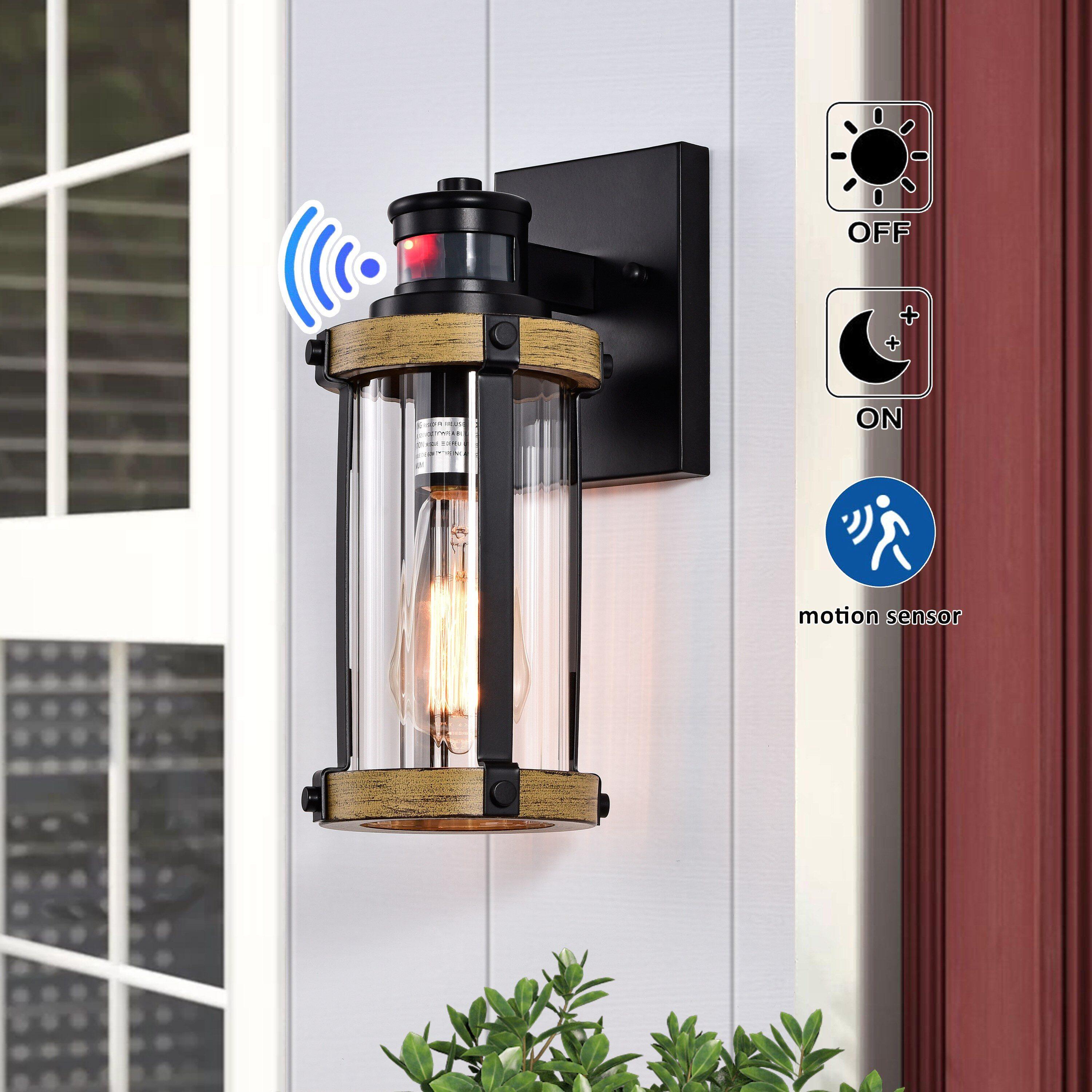 C Cattleya 5.5 in. 1-Light Motion Sensing Dusk to Dawn Outdoor Wall Sconce Black and Woodgrain Finish with Striped Clear Glass