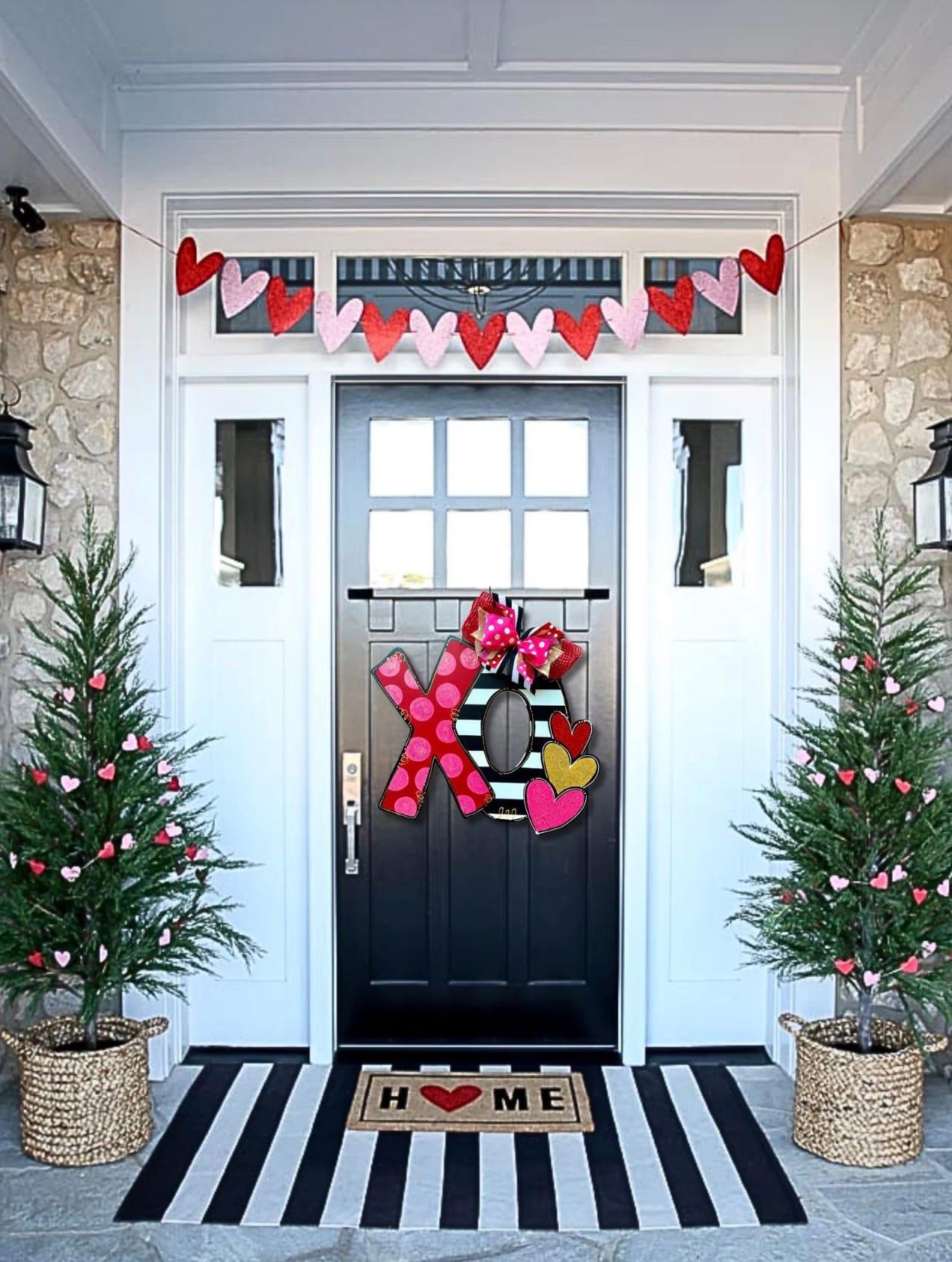 Valentine's Day porch decor consisting of an XO wreath, heart garland, and Valentine's Day Christmas trees