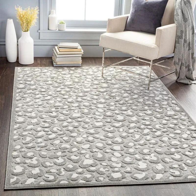 A neutral gray and white leopard print rug on the floor in the living room with a white accent chair